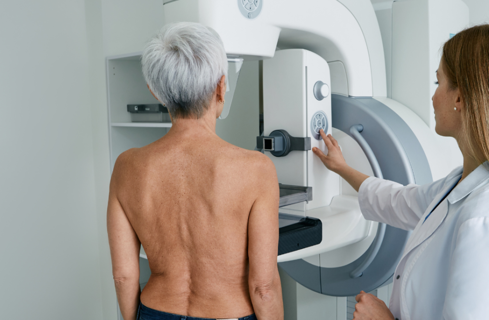 Paciente realizando exame de mamografia, utilizado em comparação com ultrassom para diagnóstico das mamas.